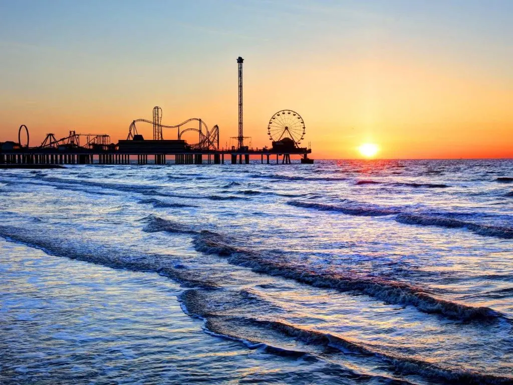 the ocean with sun setting in the distance with Pleasure Pier 
