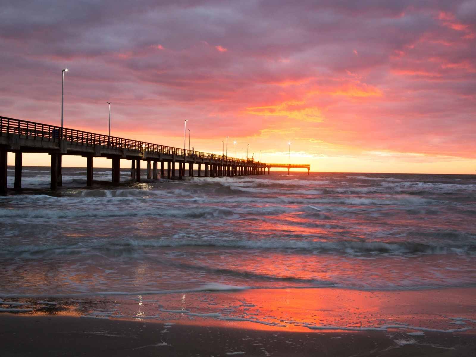 sunset over the ocean with a pier
